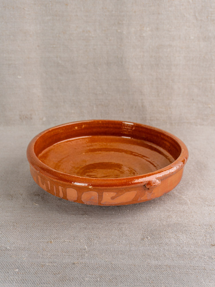 Antique French Tian glazed terracotta baking dish, early-mid 20th century, on neutral fabric background.