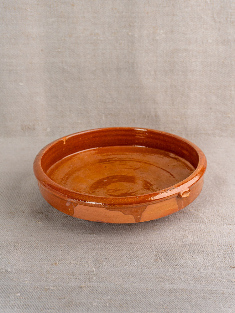 Antique French Tian glazed terracotta baking dish, early-mid 20th century, on light gray textured fabric.