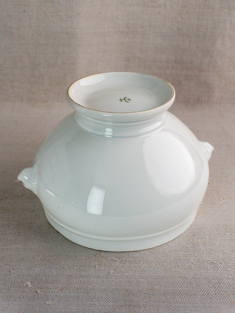 Vintage French CNP soup bowl with lion head handles, white ceramic, on beige textured fabric.