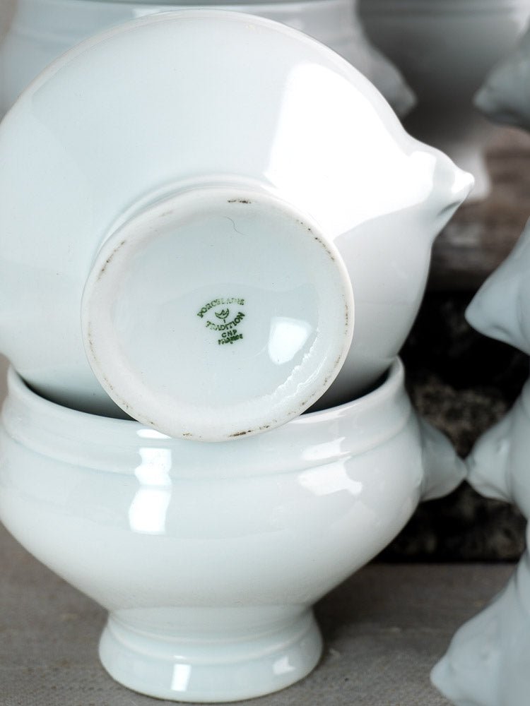 Stacked white ceramic lion head soup bowls with green French maker’s mark, glossy porcelain finish.