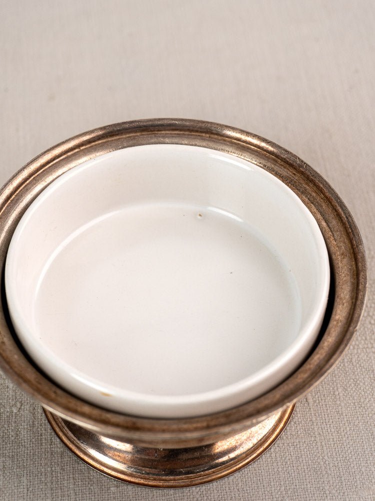 White ceramic bowl with porcelain insert nestled in a vintage Italian silver-plated coupe on textured surface.
