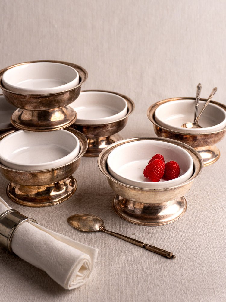 Set of six vintage Sambonet coupes with silver rims on linen, raspberries and antique spoons displayed.