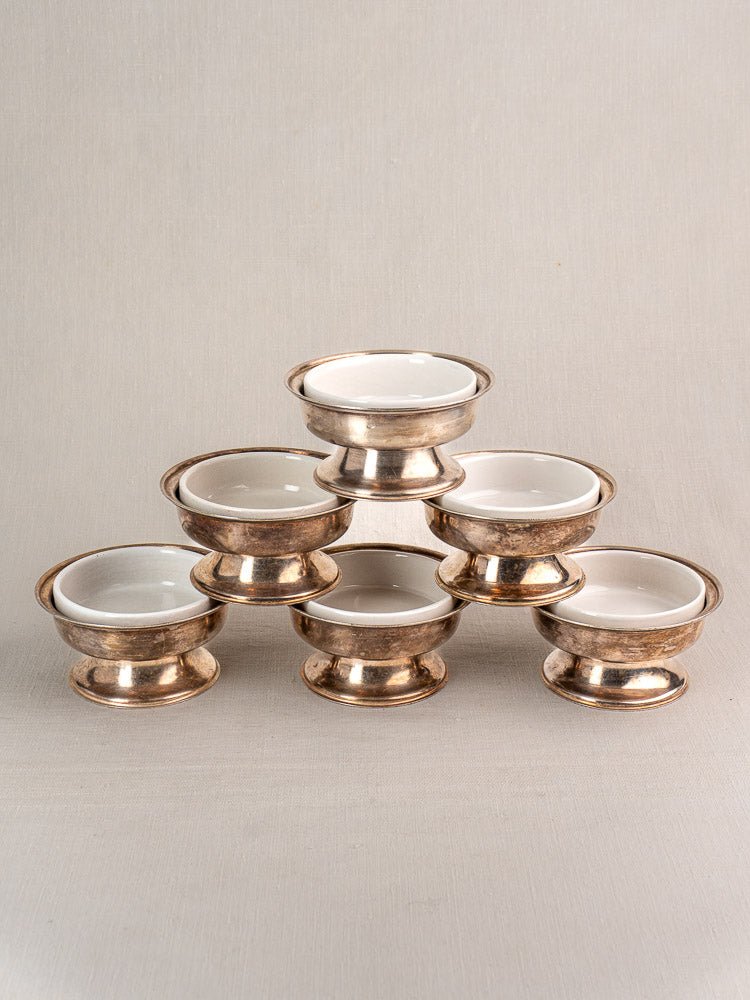 Set of six vintage Italian Sambonet silver plate coupes with white porcelain inserts, stacked on linen.