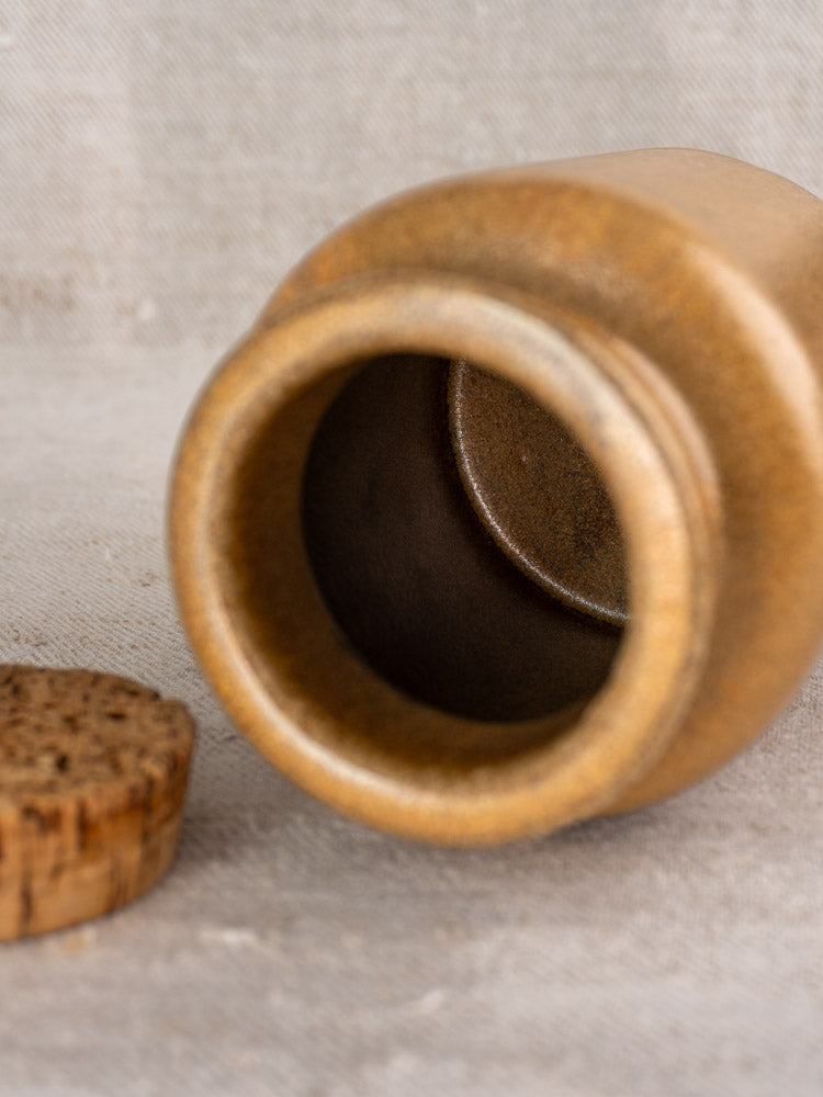 Set of three mid-century French stoneware mustard pots with cork lids on a neutral fabric background.