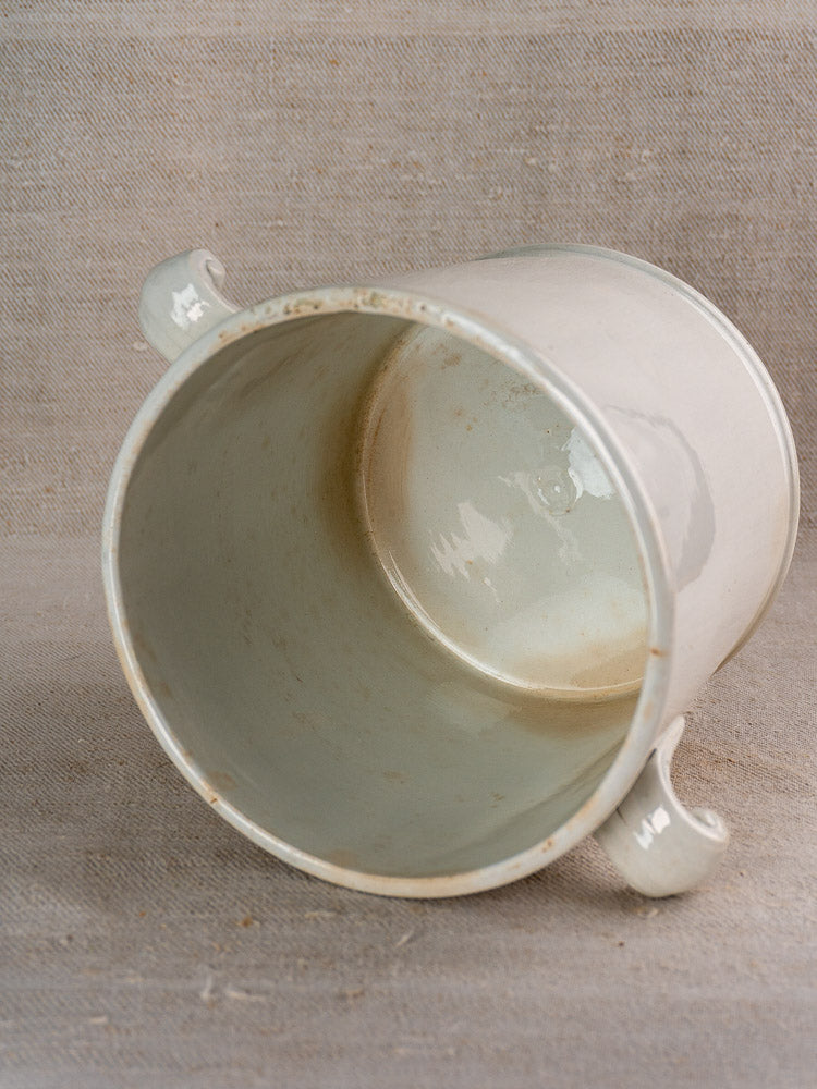 Antique French Lunéville white faience soup tureen with two handles, showing interior staining on beige fabric.