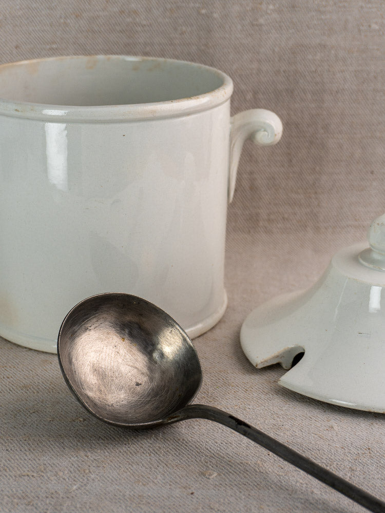 Antique French Lunéville white faience soup tureen with matching chipped lid and tarnished metal ladle.