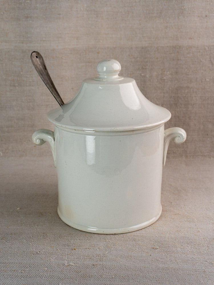 Antique French Lunéville white faience soup tureen with handles and lid, on beige fabric.