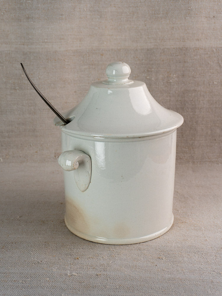 Antique French Lunéville white faience soup tureen with side handle and lid, on beige textured surface.