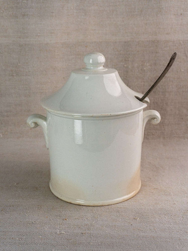 Antique French Lunéville white faience soup tureen with handles and slotted lid on fabric.