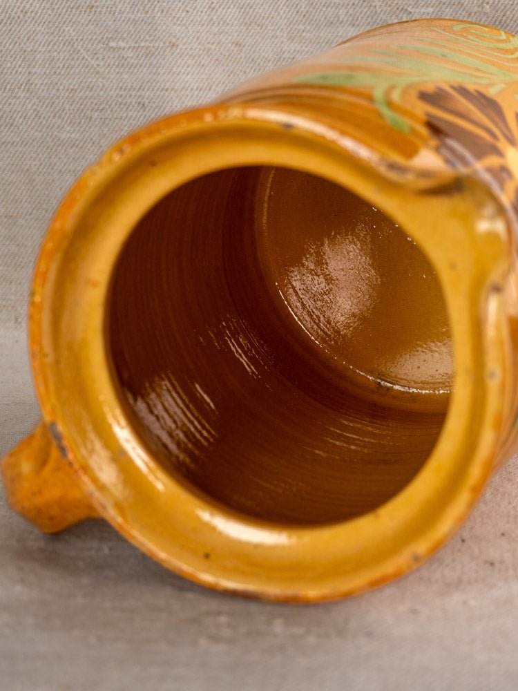 Antique French Savoyard pitcher with yellow ochre glaze and floral design, shown on textured surface.