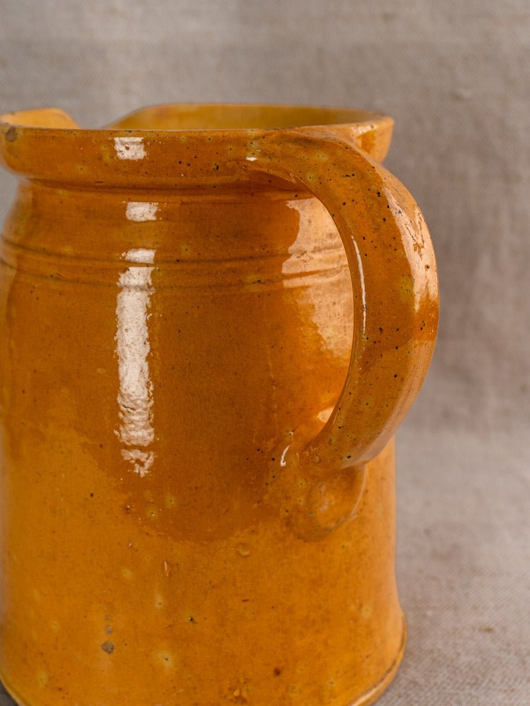 Antique French Savoyard pitcher with yellow ochre glaze and hand-painted floral details on neutral background.