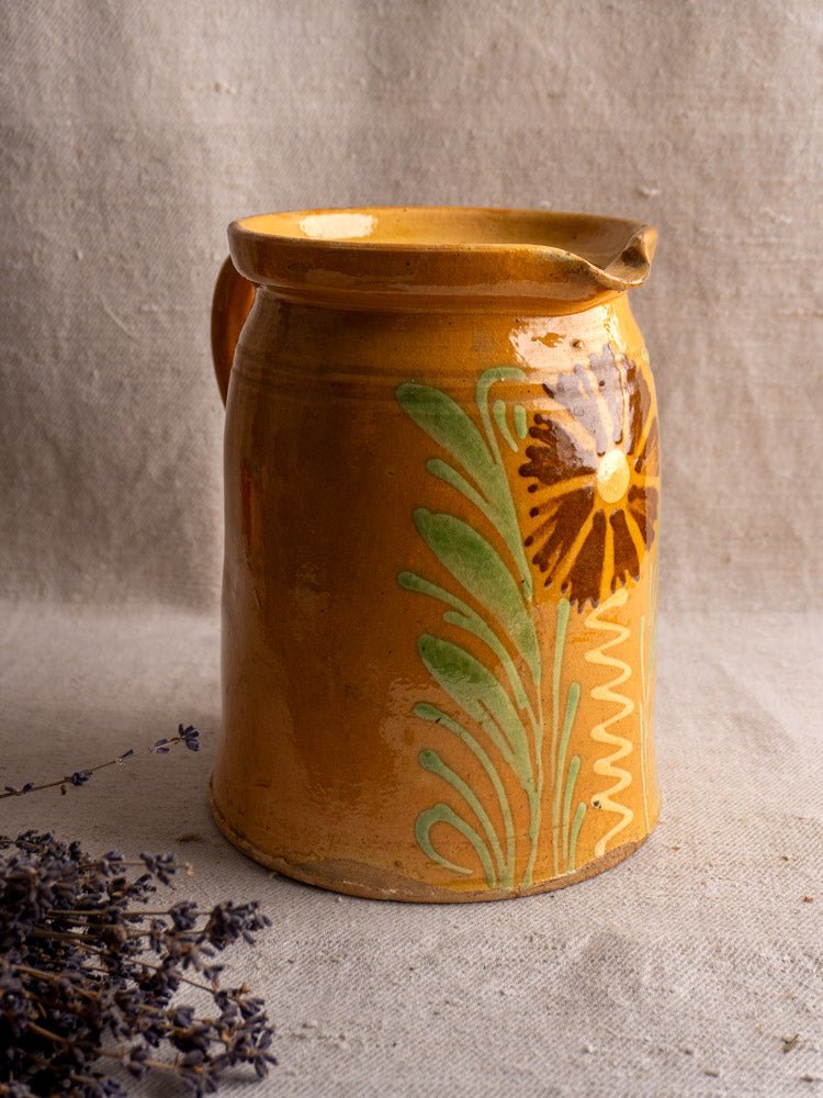Antique French Savoyard pitcher with yellow ochre glaze and floral design beside dried lavender.