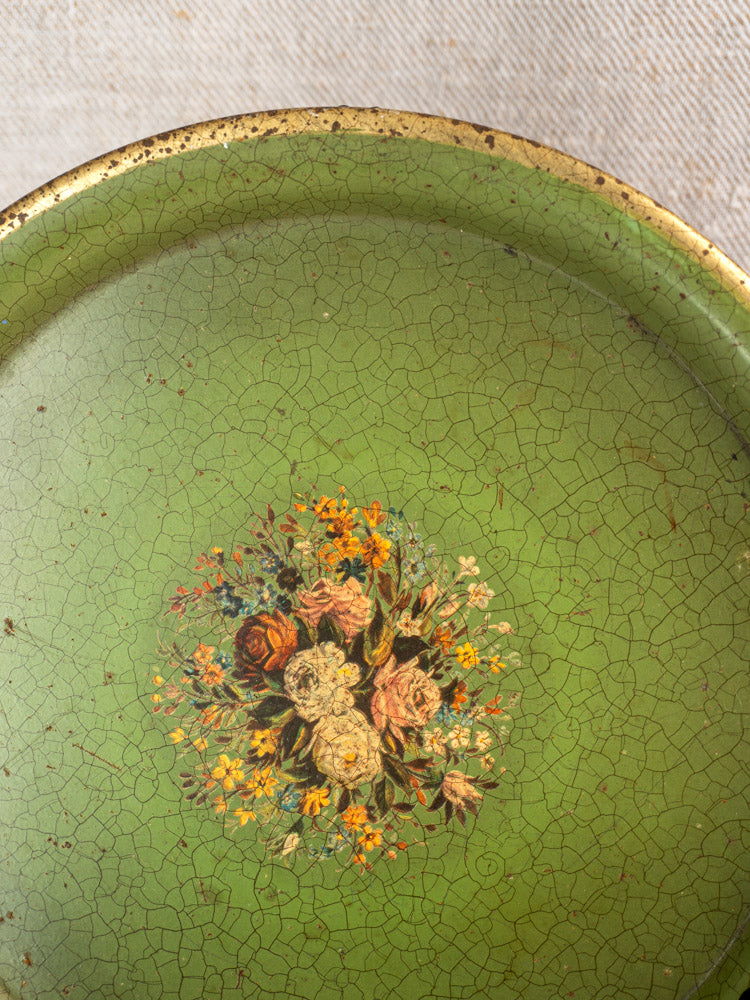 Round green antique French painted tôle tray, c. 1900, with central floral bouquet and aged cracked texture.
