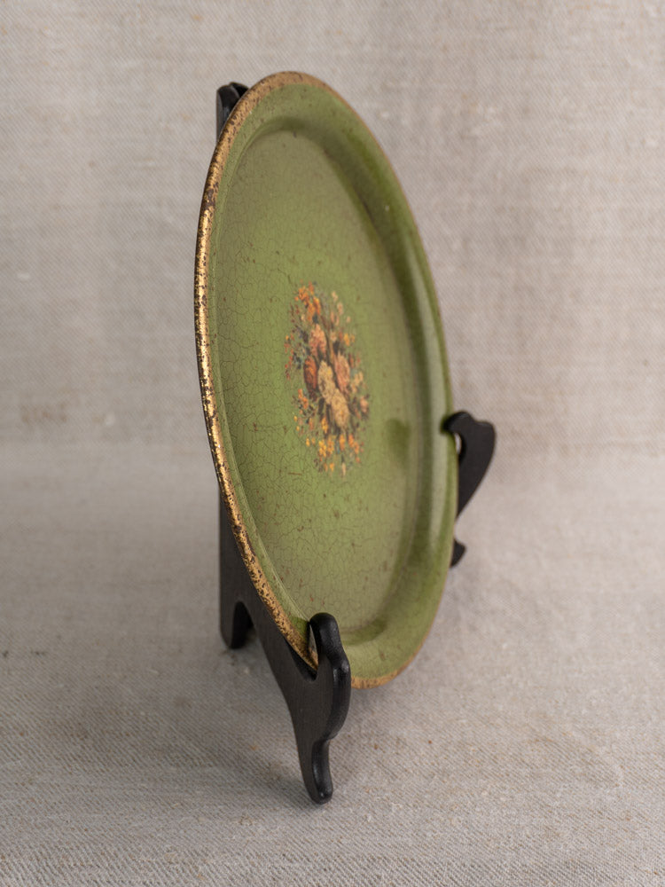 Antique French painted tôle tray, green with floral motif and gold rim, on black stand.
