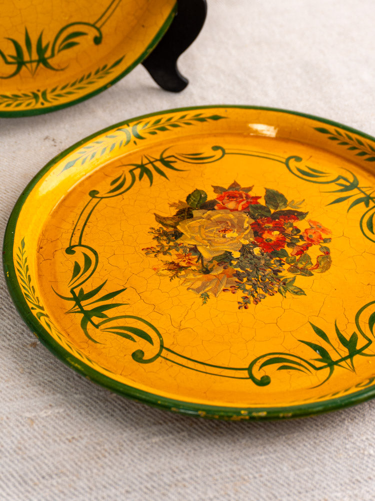 Pair of round antique French painted tôle trays, yellow metal with green border and floral centers.