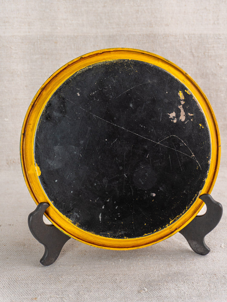 Antique French painted tole tray, round with black center, yellow rim, and aged patina.