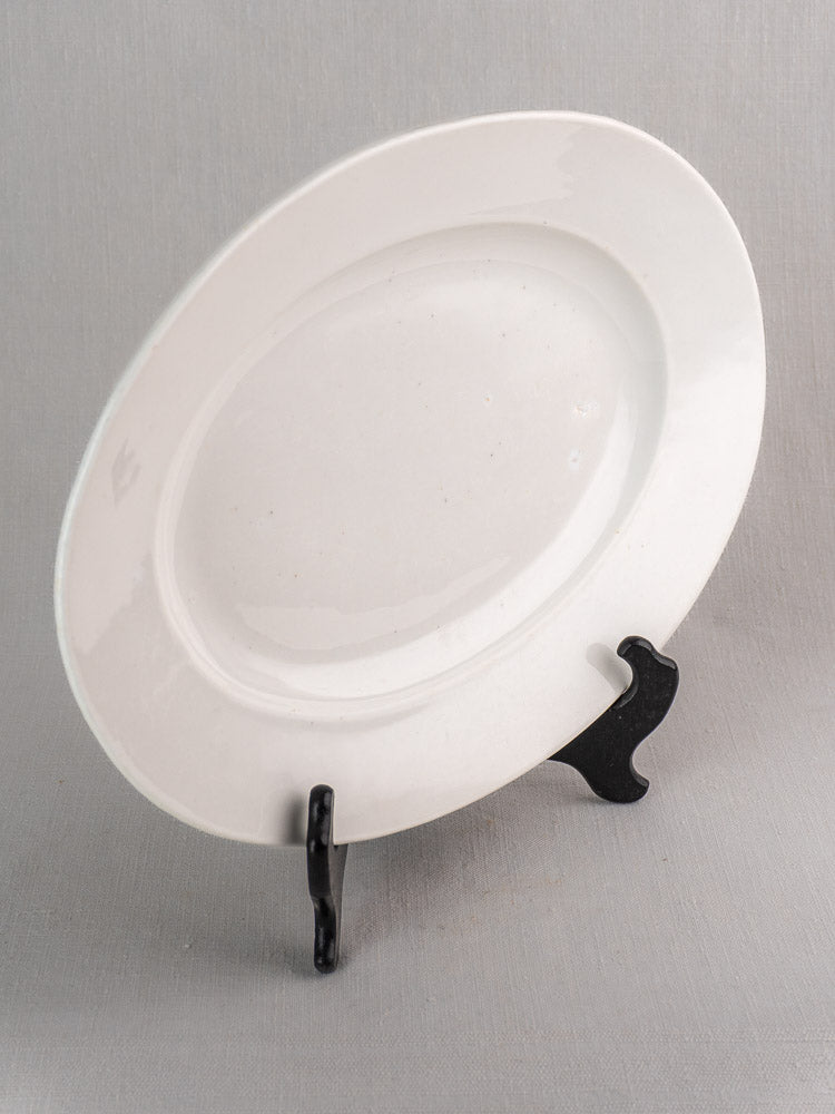 Pair of antique French white ironstone oval platters on black stand with light gray background.