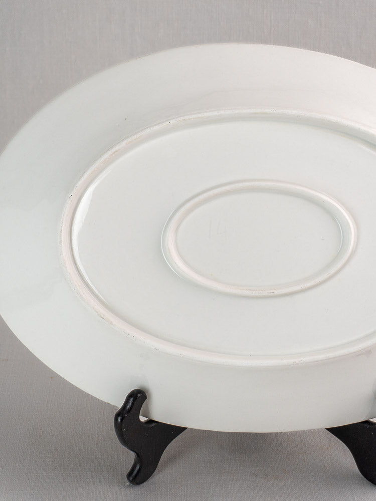 Pair of antique French white ironstone oval platters in graduated sizes on black stand, light gray background.