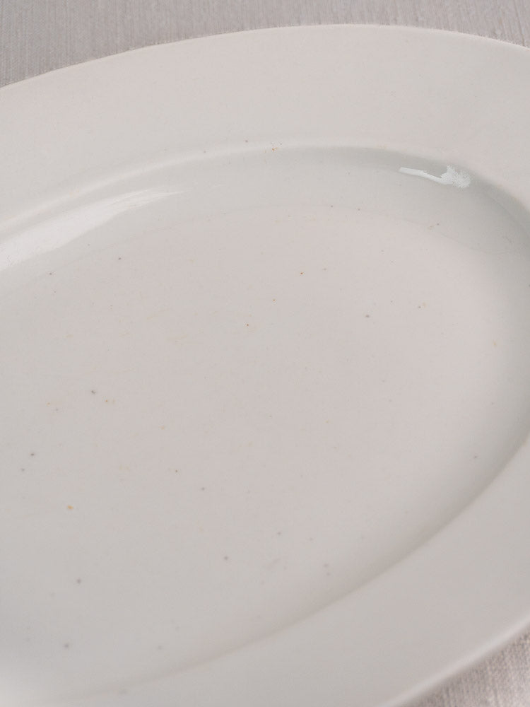 Antique French white ironstone oval platter with smooth surface and classic design, angled view.