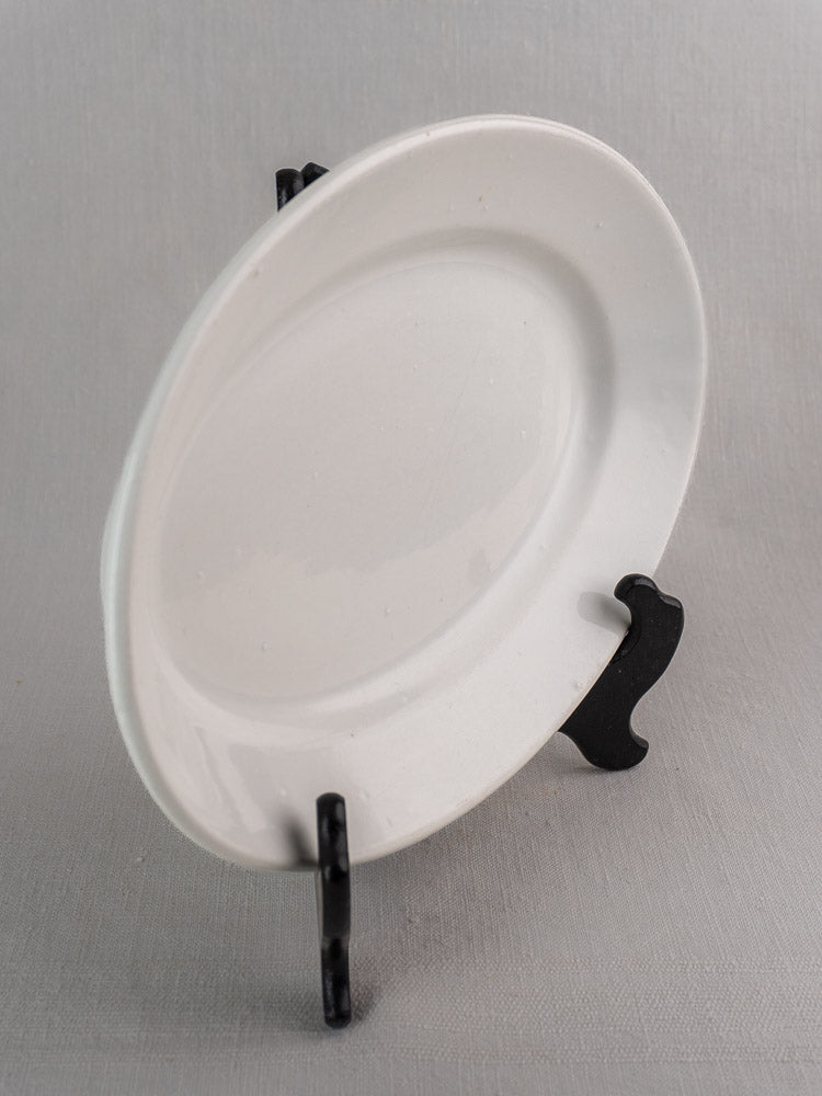 Pair of antique French white ironstone oval platters in graduated sizes on black stand, light gray background.