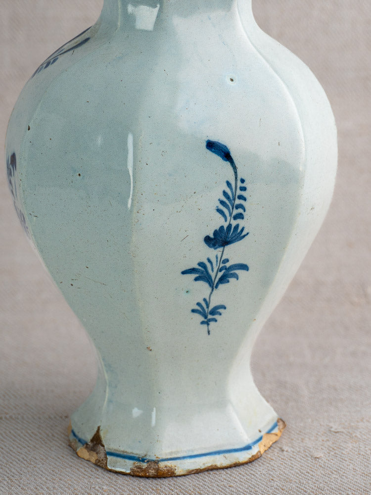 Antique Dutch Delft vase pair, c.1700, blue floral motifs, faceted bodies, chip at foot, neutral fabric backdrop.