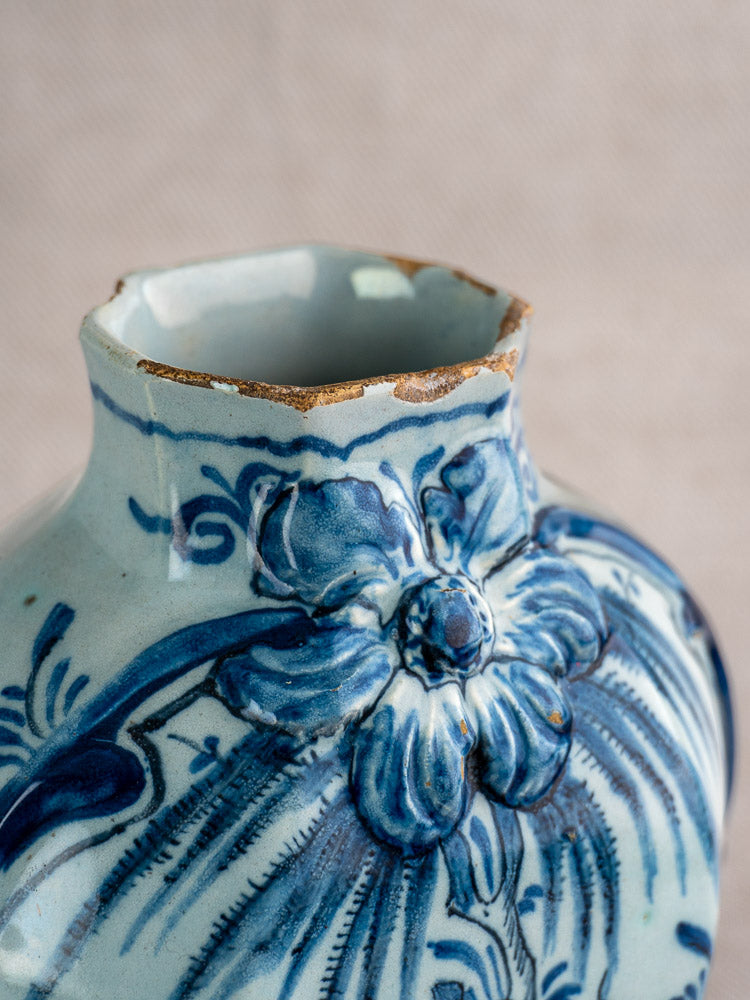 Antique Dutch Delft blue and white vase pair with floral relief, chipped rim reveals brown ceramic beneath glaze.