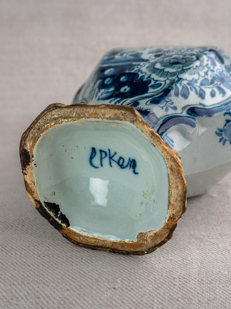Base of antique Dutch Delft vase, c. 1700, blue and white ceramic marked "EPKER," on textured beige surface.