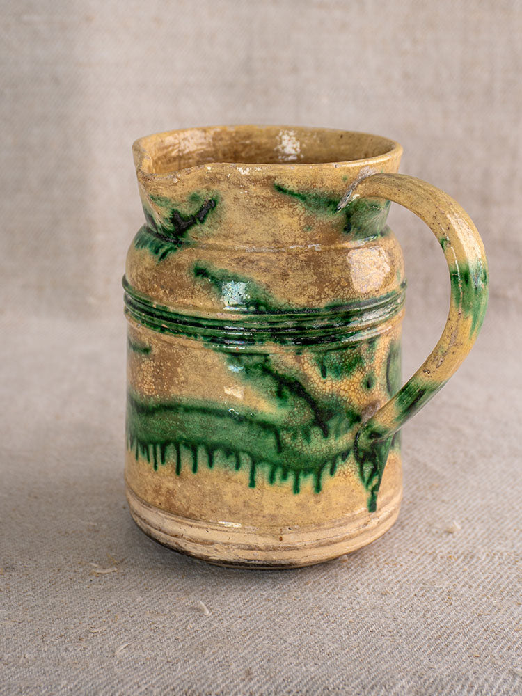 Antique French Jaspé pitchers from Dieulefit with green glaze and marble streaks on beige textured fabric.