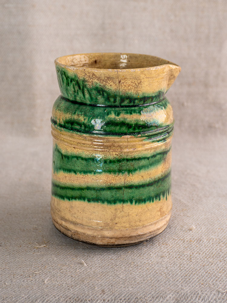 Pair of antique French Jaspé pitchers with green glaze from Dieulefit on textured beige fabric.