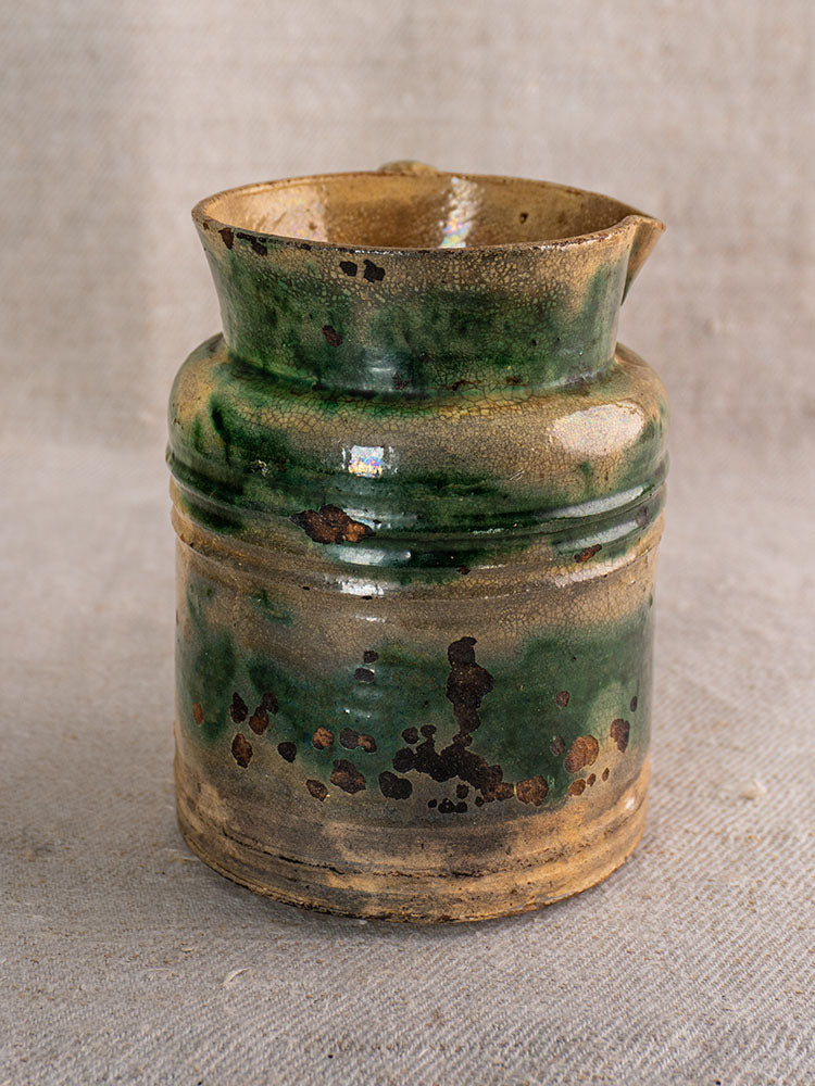 Pair of antique French jaspé pitchers with green glaze from Dieulefit on textured beige fabric.