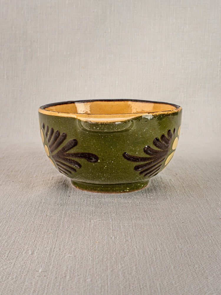 Pair of vintage French Savoyard green glazed bowls with handles, brown accents, and yellow interiors on fabric.