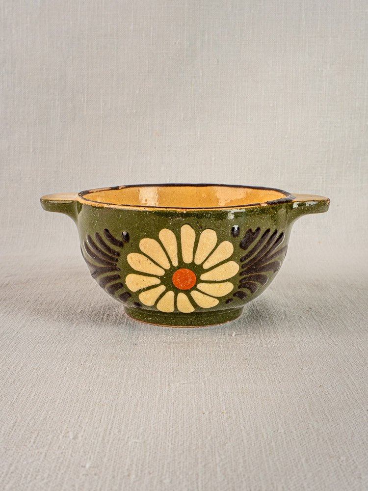 Vintage French green glazed bowl with side handles, daisy motif, and yellow interior.
