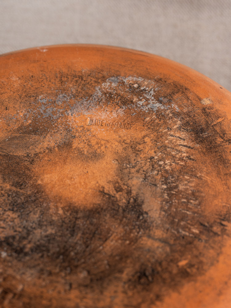 Antique French glazed terracotta poêlon with MADE IN FRANCE stamp, weathered orange-brown finish, stains, and scratches.