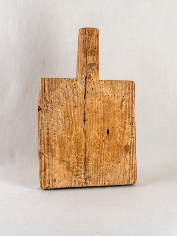 Antique 18th-century French cutting board with handle, visible wood grain, wear, and age cracks.