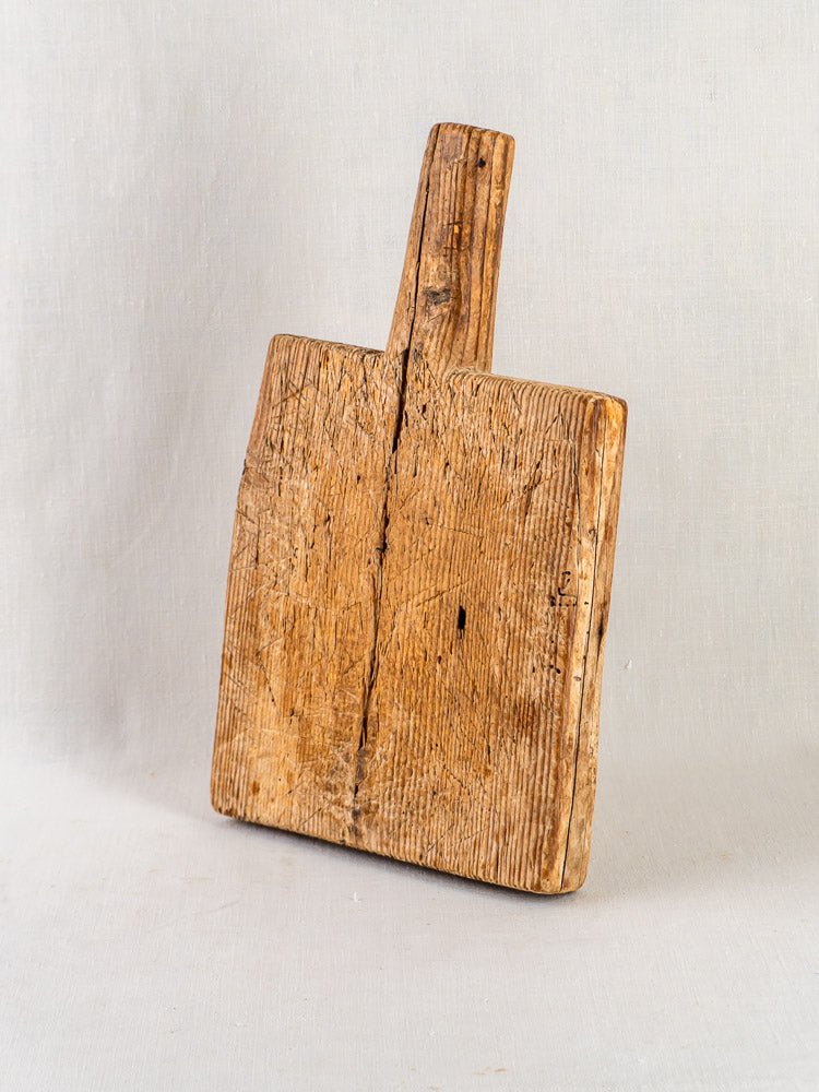 Antique 18th-century French primitive cutting board with handle, weathered wood, rustic patina.