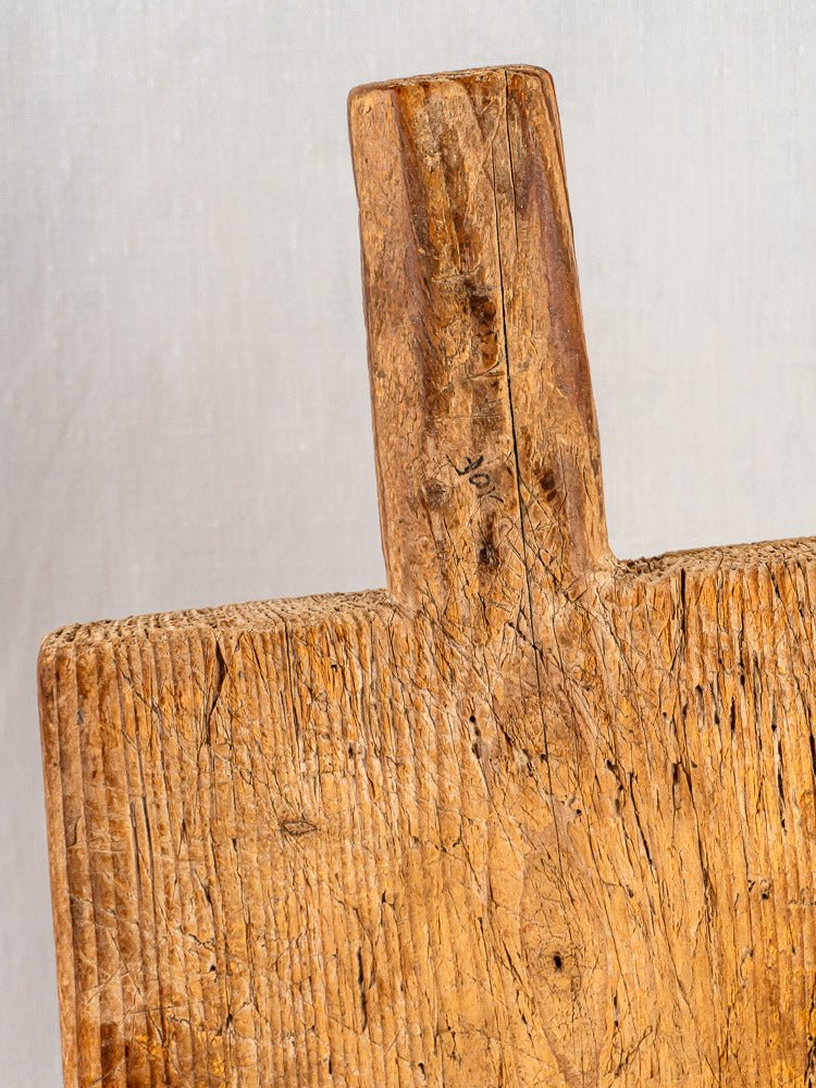 Antique 18th-century French primitive cutting board with handle, rich wood grain, and weathered texture.