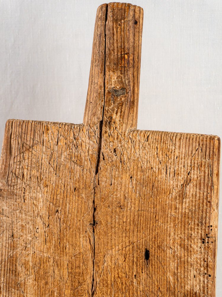 French antique primitive cutting board with rustic handle, worn surface, and rich wood grain on light background.