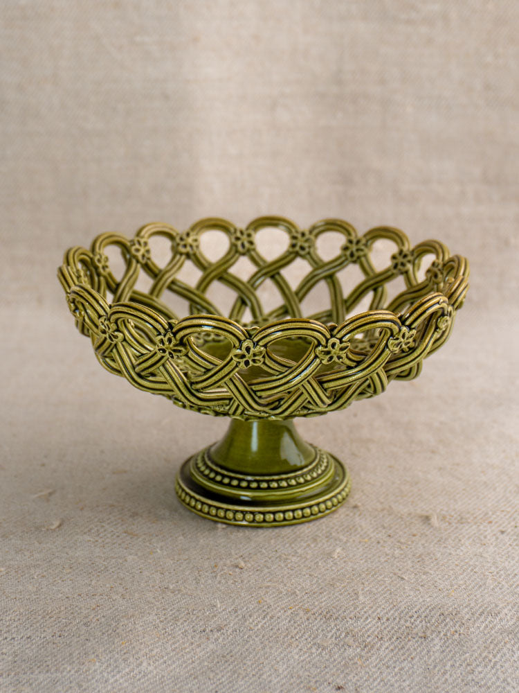 Antique French Pichon Uzès olive green compote with openwork pedestal, set against textured beige fabric.