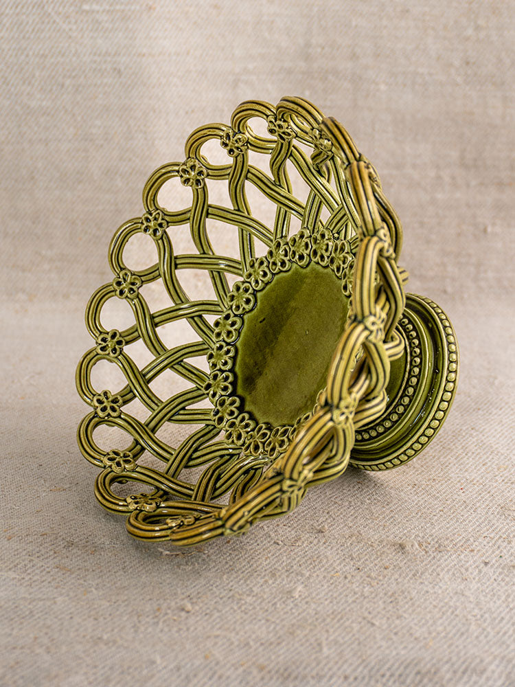 Antique French Pichon Uzès olive green compote with openwork and pedestal base on neutral fabric background.