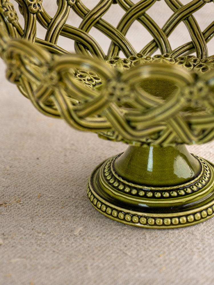 Antique French Pichon Uzès olive green compote, openwork pedestal basket with intricate pattern, on textured beige surface.