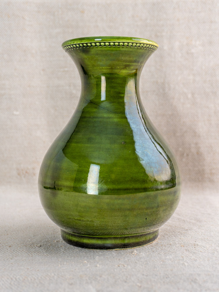 Vintage French Pichon Uzès green glazed earthenware vase with wide body and decorative rim on beige textured surface.