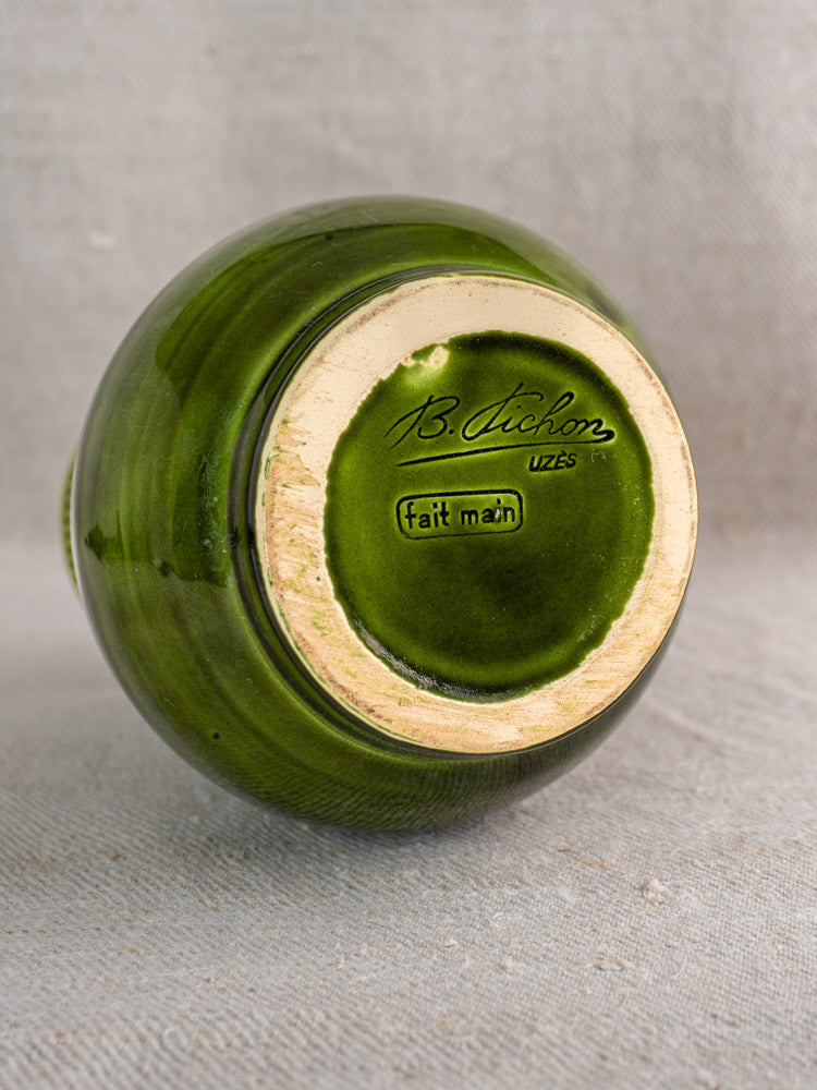 Mid-century French Pichon Uzès green glazed earthenware vase, upside down on beige fabric, showing signed tan base.