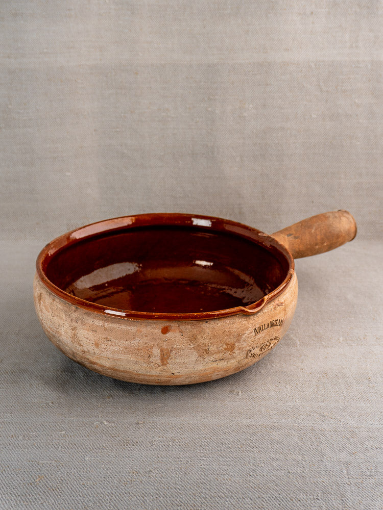 Vintage French Vallauris Poêlon ceramic pan with glazed interior and rustic unglazed exterior on fabric.