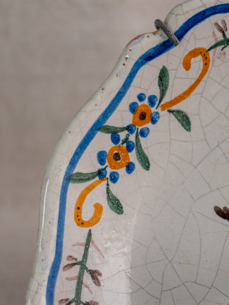 Antique French faience plate with scalloped rim, hand-painted floral motifs, and crackled glaze, 19th century.