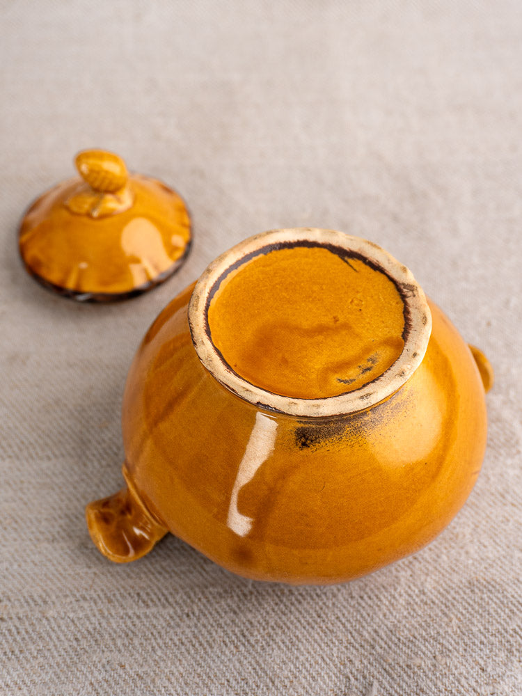 Vintage French demitasse coffee cup in honey-glazed earthenware with matching lid on a textured surface.