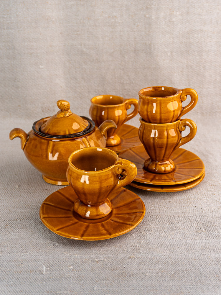 French vintage honey-glazed earthenware demitasse set with teapot, four cups, and saucers on beige surface.