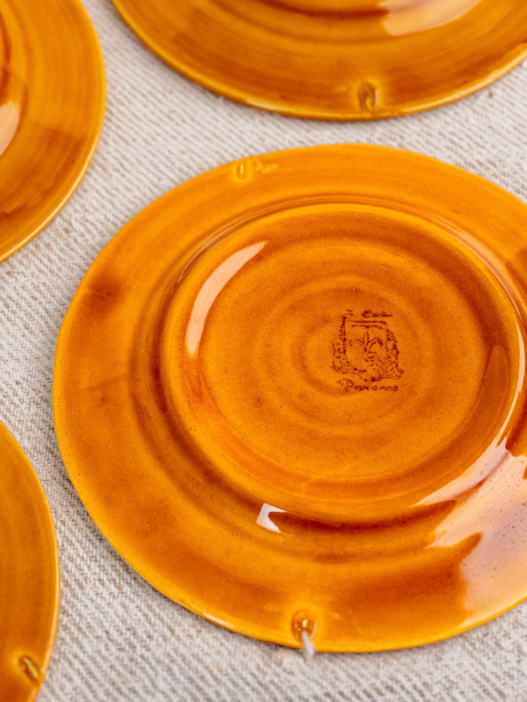 Vintage French demitasse coffee set plate with amber honey glaze and central maker’s mark on beige fabric.