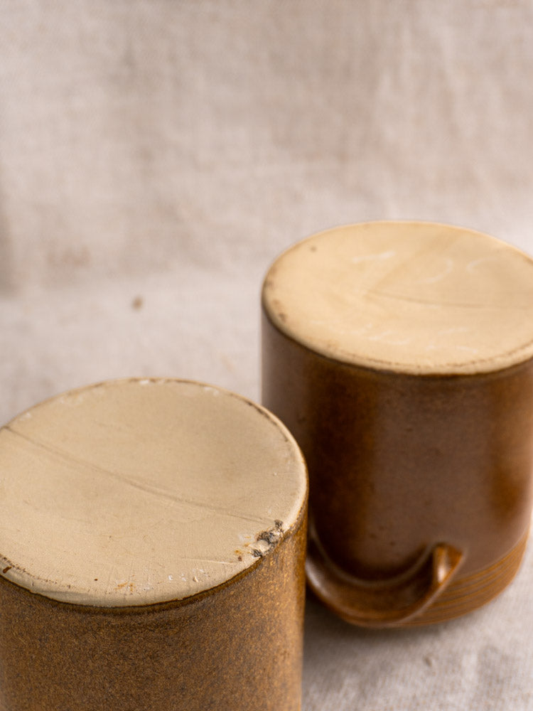 Pair of vintage French Digoin Grespots stoneware pots, beige bases and brown sides, on fabric.
