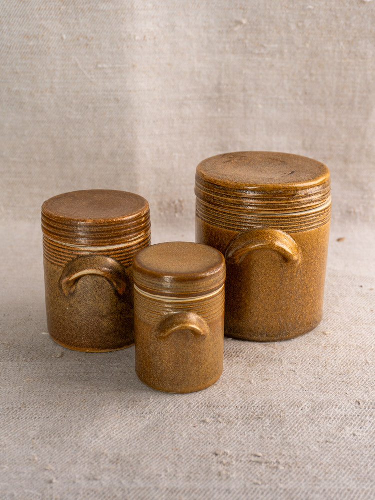 Set of five vintage French Digoin Grespots stoneware pots on a textured beige fabric backdrop.