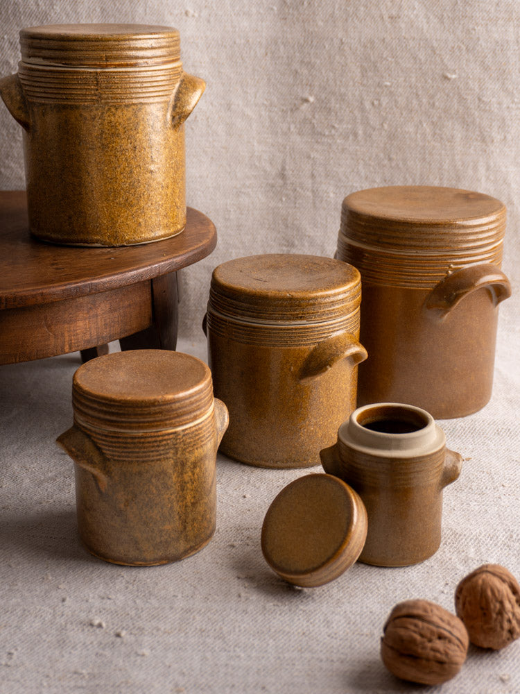 Set of five vintage French Digoin Grespot stoneware pots with lids, some open, on fabric.